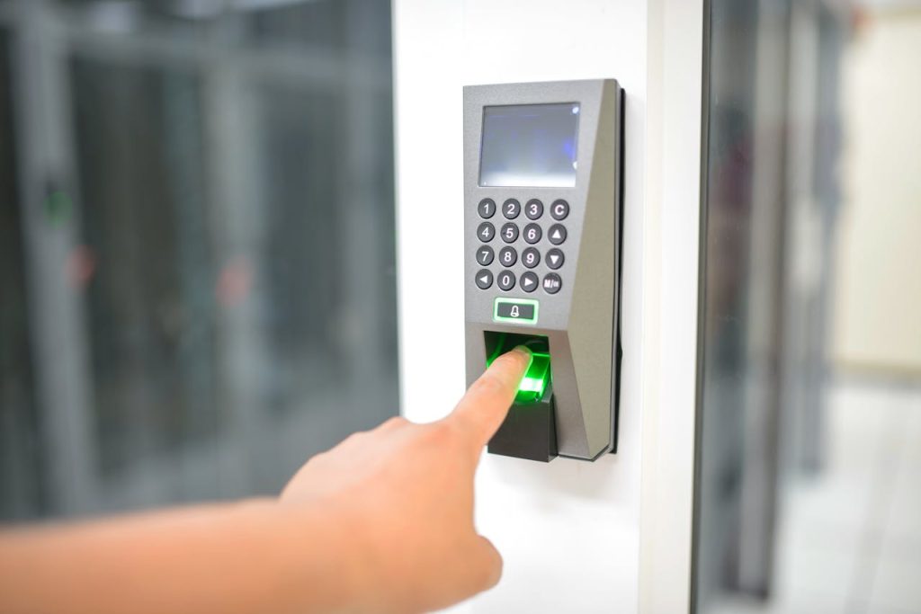 finger-scan-17155842 A person uses a fingerprint scanner for secure entry in a business setting.